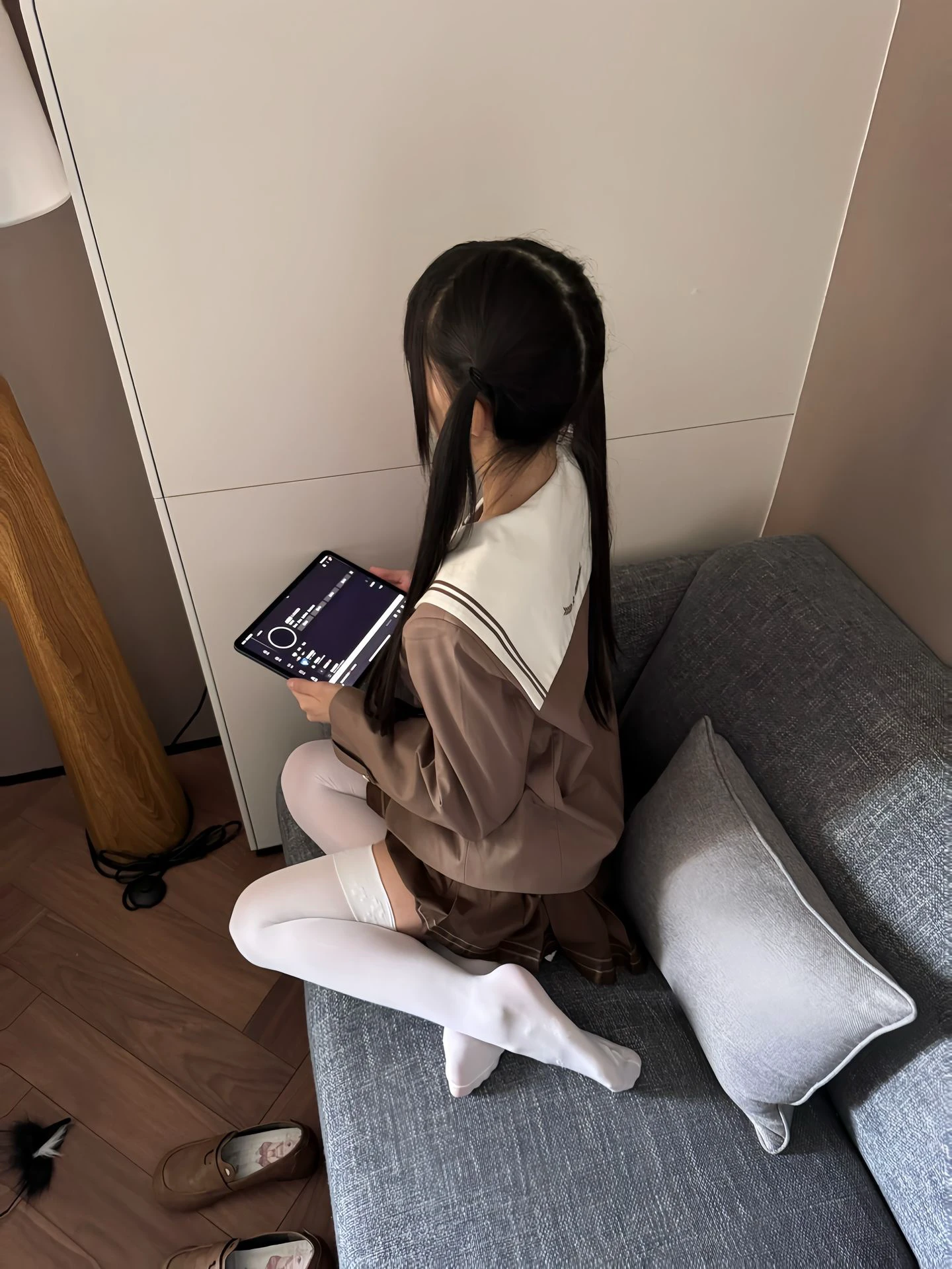 女孩捧着平板电脑坐在沙发上