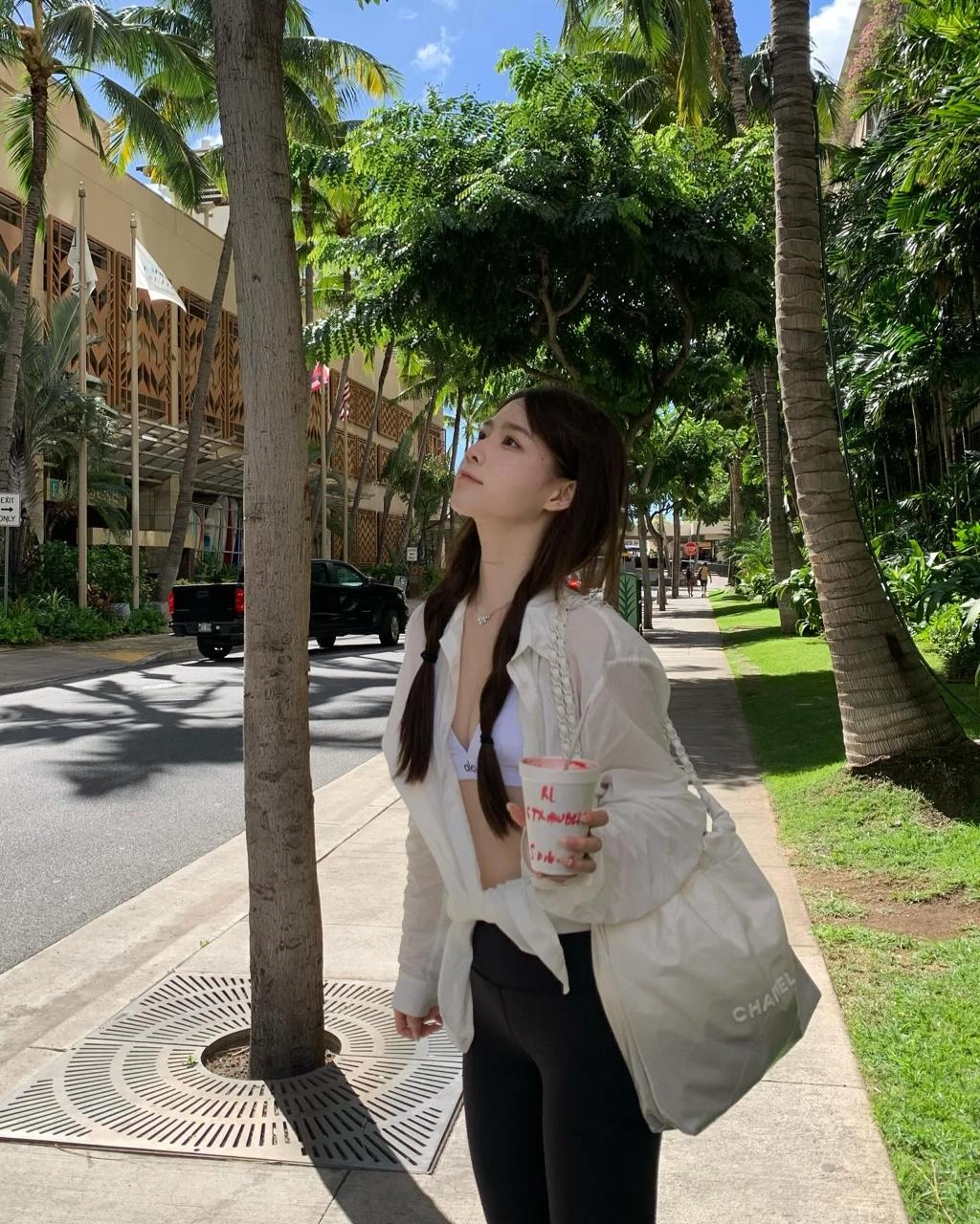 穿着白色衬衫和黑色短裤的女人正在拿着一个杯子。