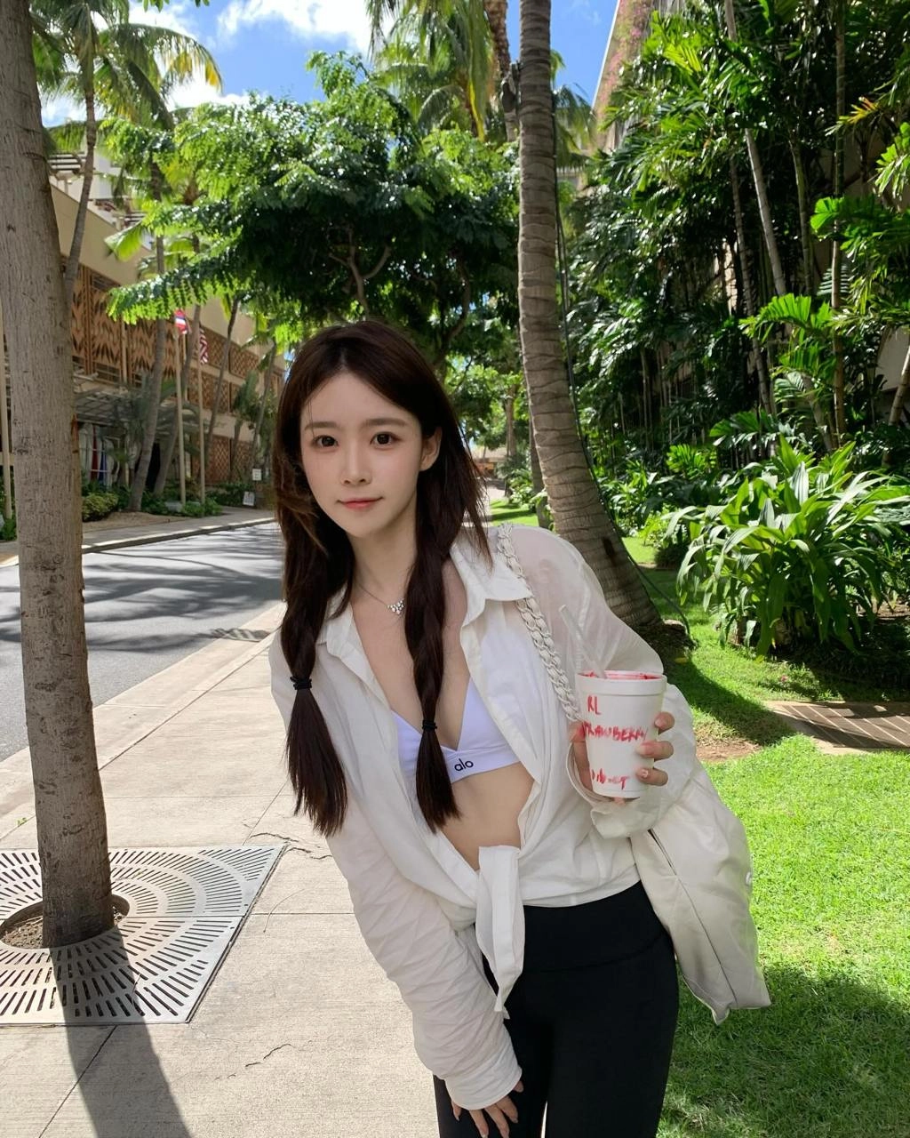 穿着白色衬衫和黑色短裤的女人正在拿着一个杯子。