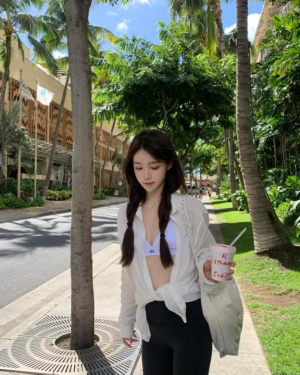 穿着白色衬衫和黑色短裤的女人正在拿着一个杯子。