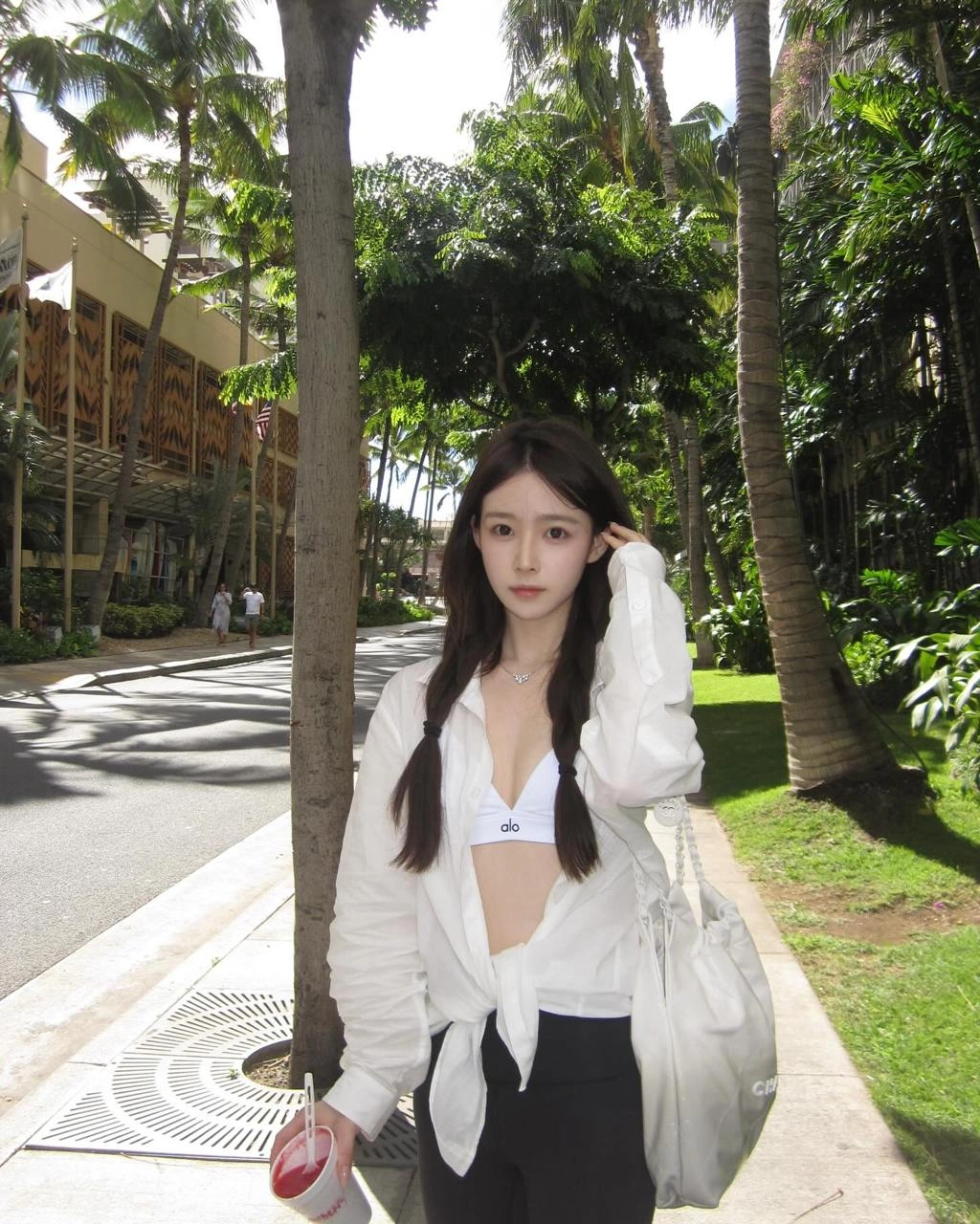 穿着白色衬衫和黑色短裤的女人正在拿着一个杯子。