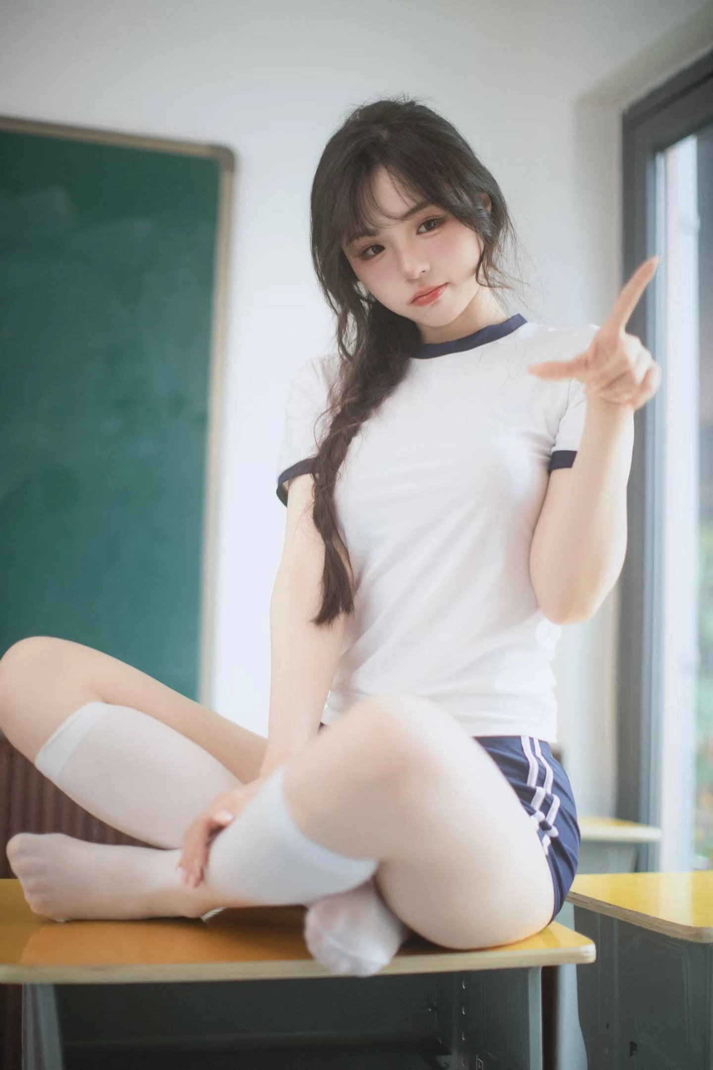 穿着白色衬衫和蓝色短裤的女孩指向相机。