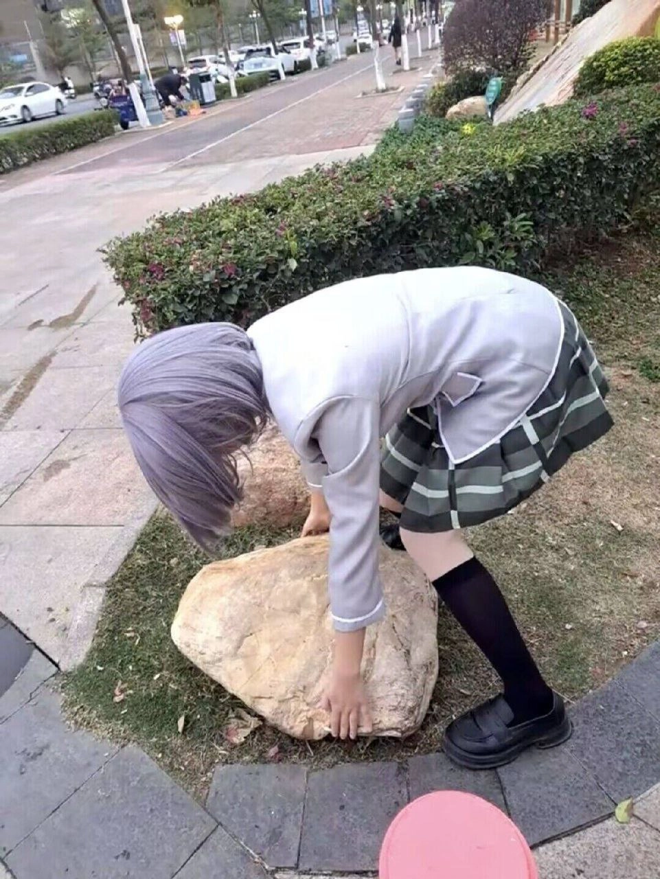 一位穿着白色外套的女人向前弯曲,拿起一块石头。