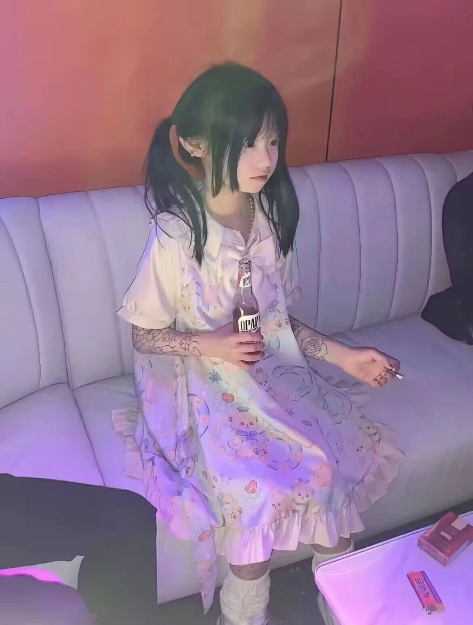 年轻的女孩有纹身和一瓶苏打。