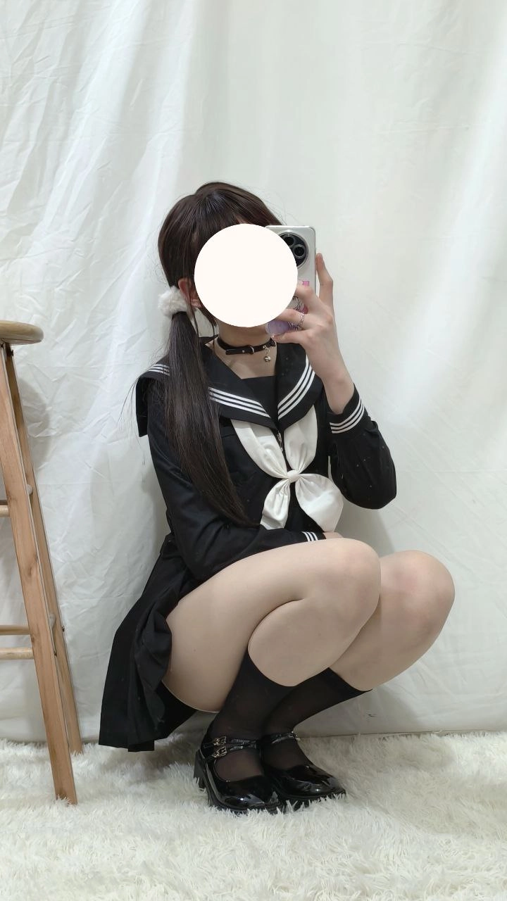 一位穿着黑色和白色的水手服的女人拍了一张自拍。