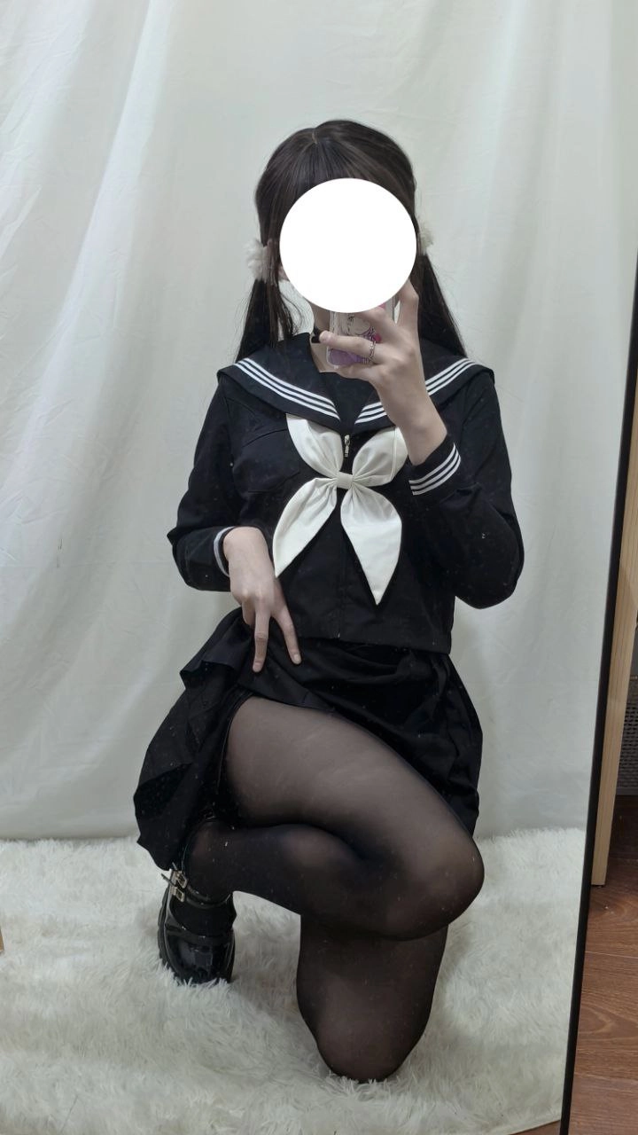 一位穿着黑色和白色的水手服的女人拍了一张自拍。