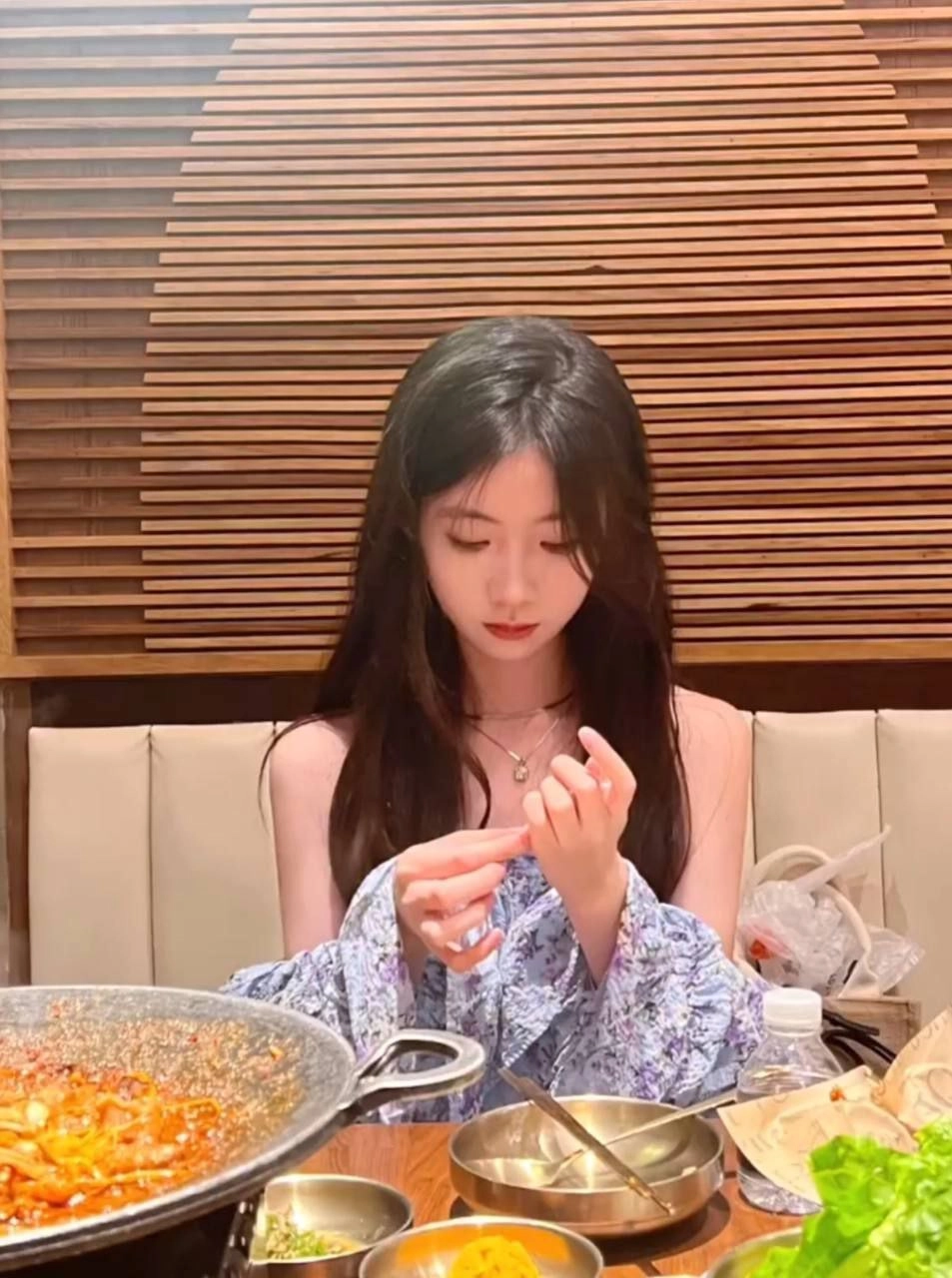 长头发的女人坐在一张桌子上,看着她的手。