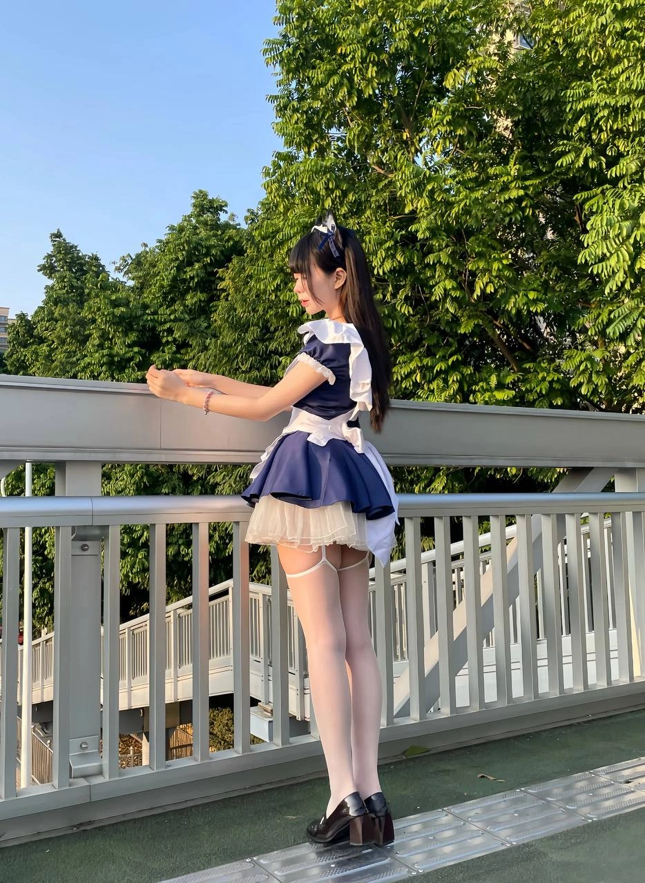 一位穿着女仆服的女人站在一座桥上。