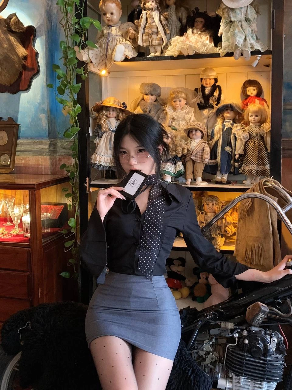 一位穿着黑色衬衫和领带的女人用一系列娃娃展现。