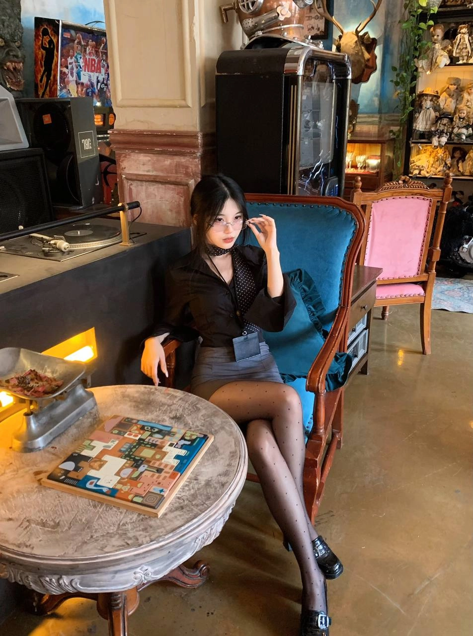 一位穿着黑色衬衫和领带的女人用一系列娃娃展现。