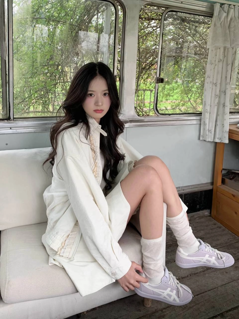 女人坐在一个凳子上,戴着一件白色衬衫和白袜子。