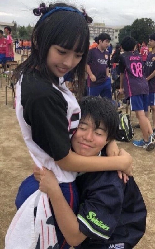 女孩拥抱一个穿着足球衬衫的男孩。