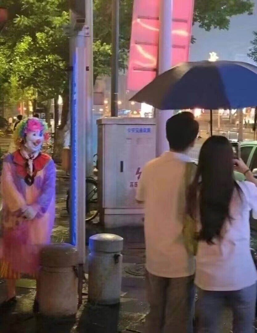 男人和一个女人站在雨伞下,一个女人拍了一张男人的照片。