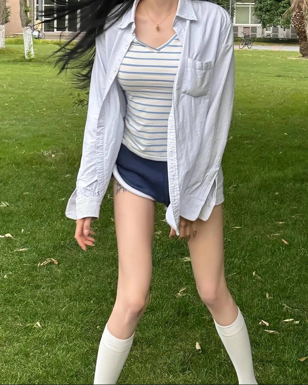 黑头发和手臂上的纹身的女人穿着带带的衬衫和短裤。