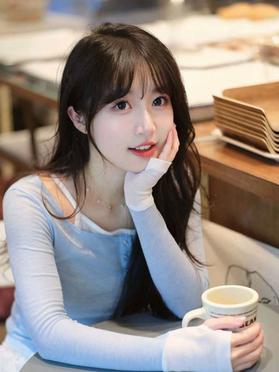 长头发和蓝衬衫的女人拿着一个杯子。