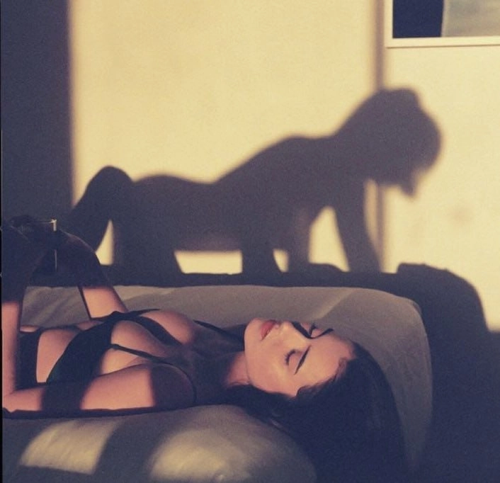 女人躺在床上,墙上有一只猫的影子。