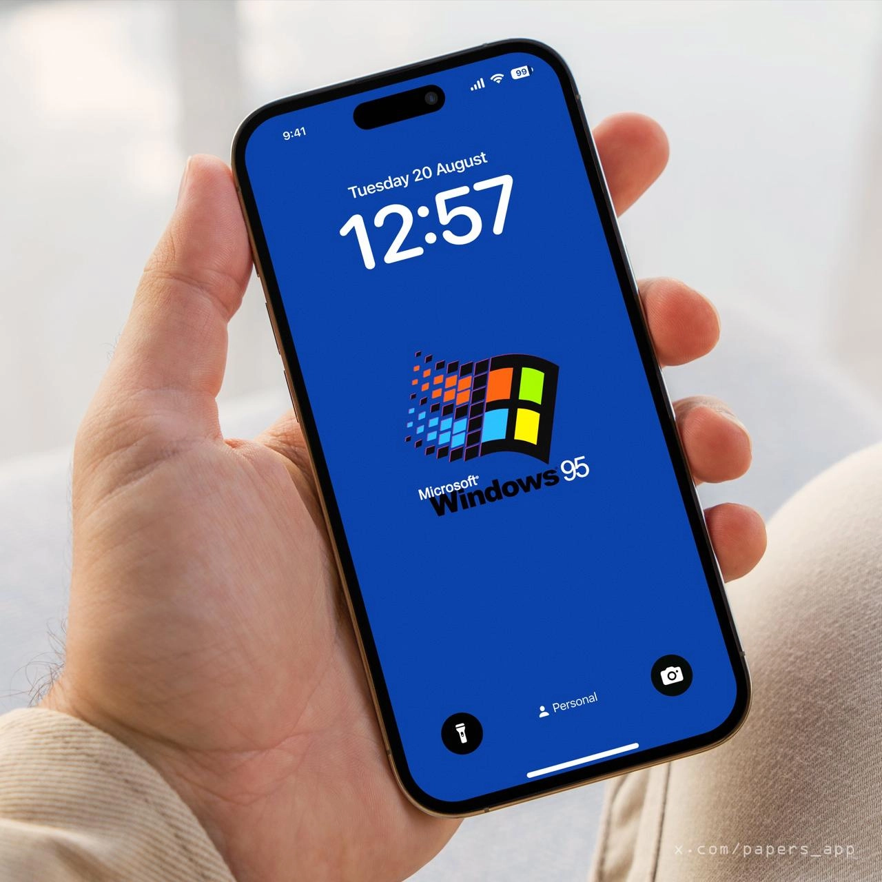 一只手拿着蓝色手机,显示时间为12:57。
