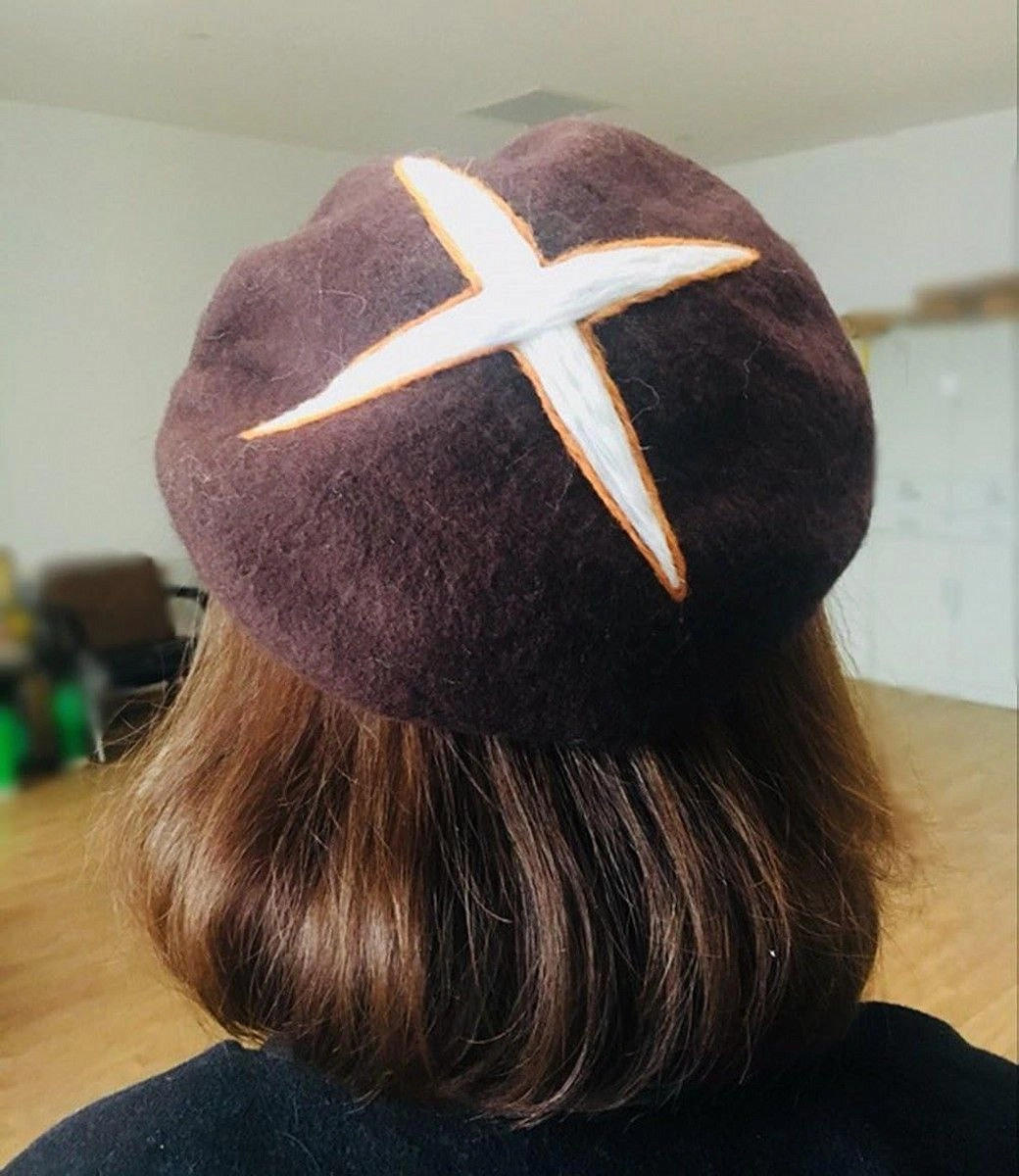 女人戴着一个棕色帽子,上面有橙色的十字架。