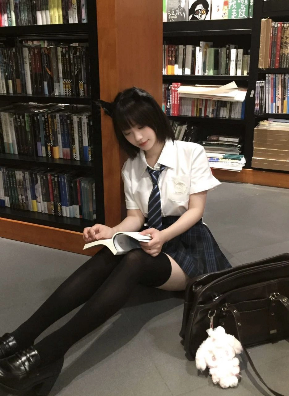 女孩坐在地板上,手里拿着一本书。