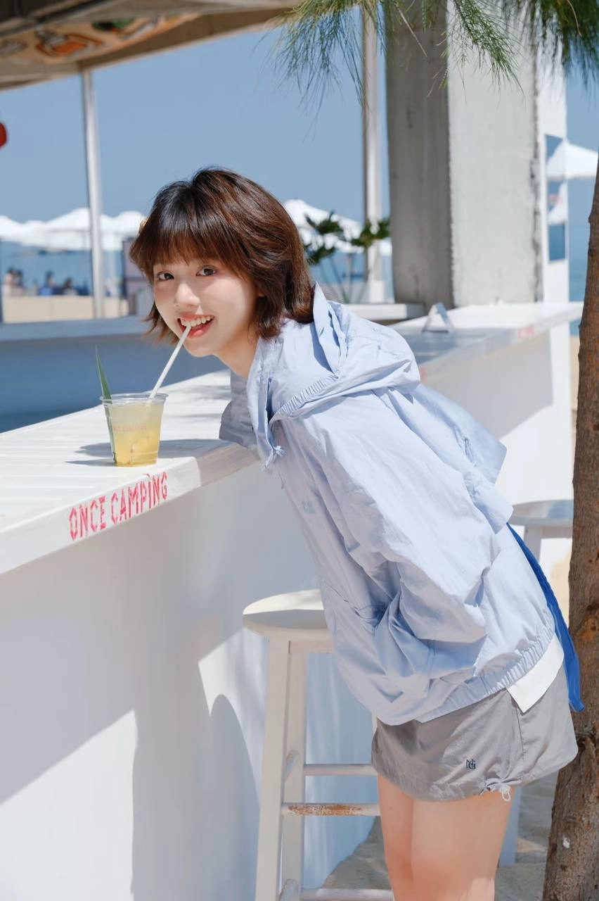 女人穿着蓝色夹克和丝带衬衫倾斜在一个柜台上。