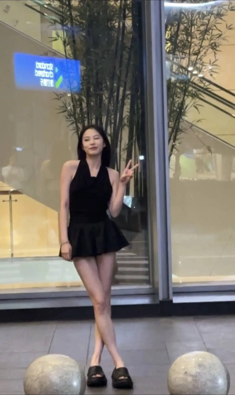 一位穿着黑色裙子和黑色胸罩的女人站在窗前。