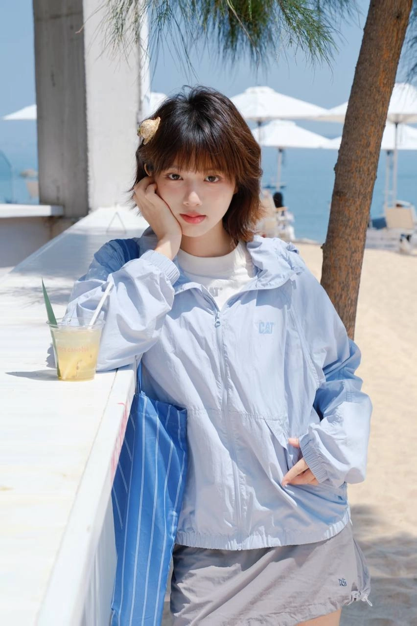 女人穿着蓝色夹克和丝带衬衫倾斜在一个柜台上。