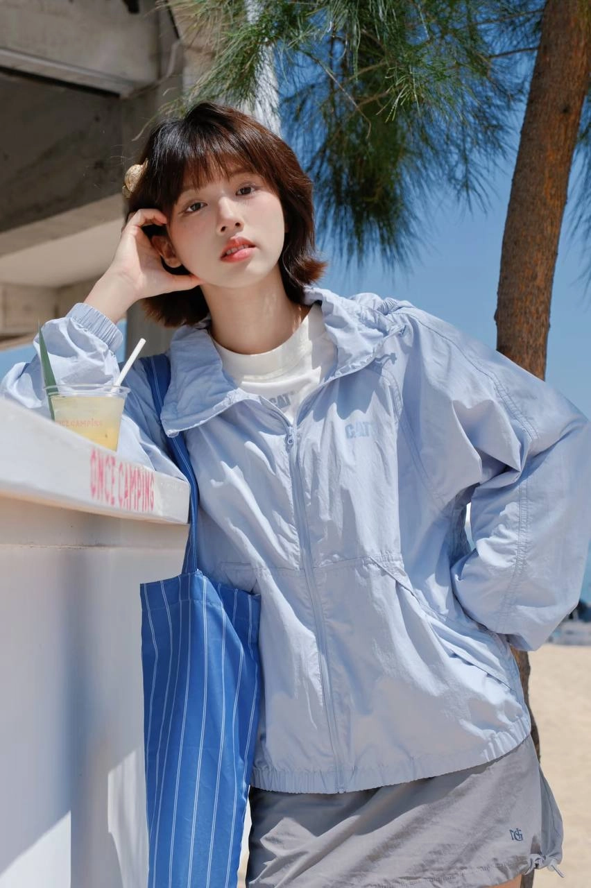 女人穿着蓝色夹克和丝带衬衫倾斜在一个柜台上。