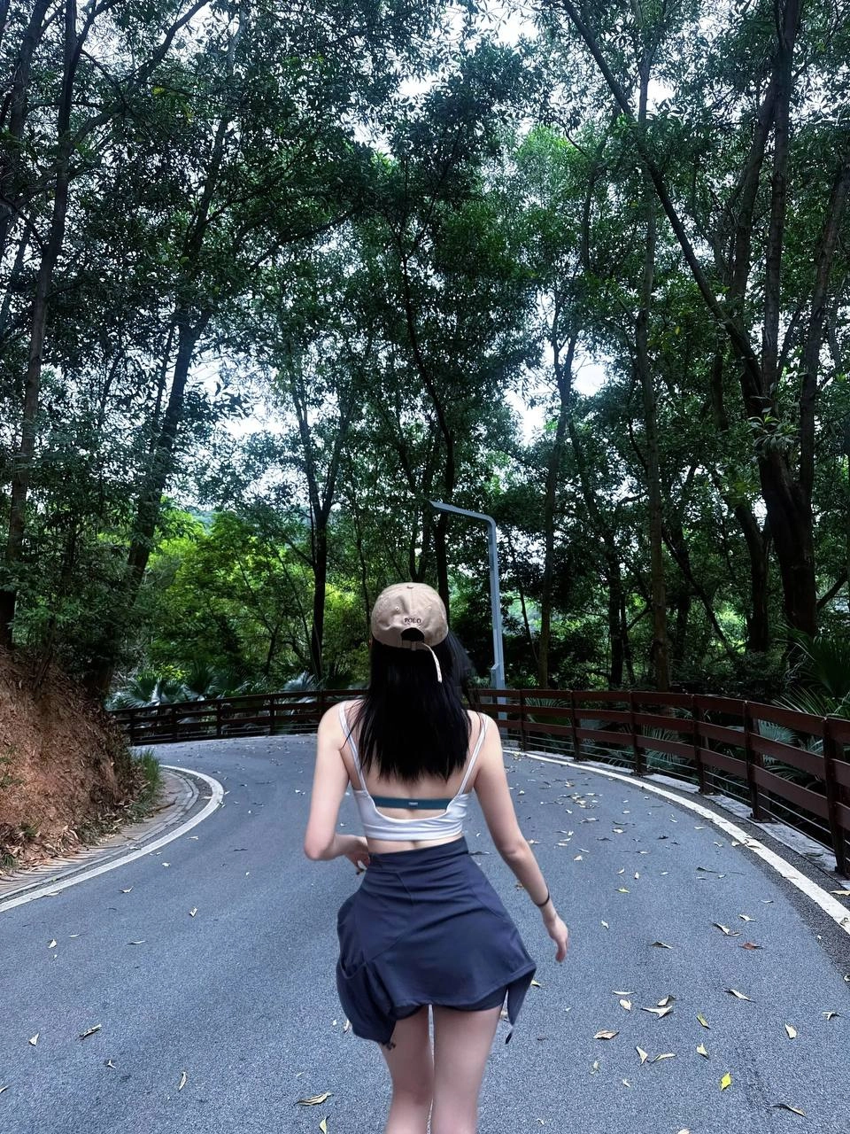 一位穿着棕色帽子和黑色短裤的女人在路上滑板。