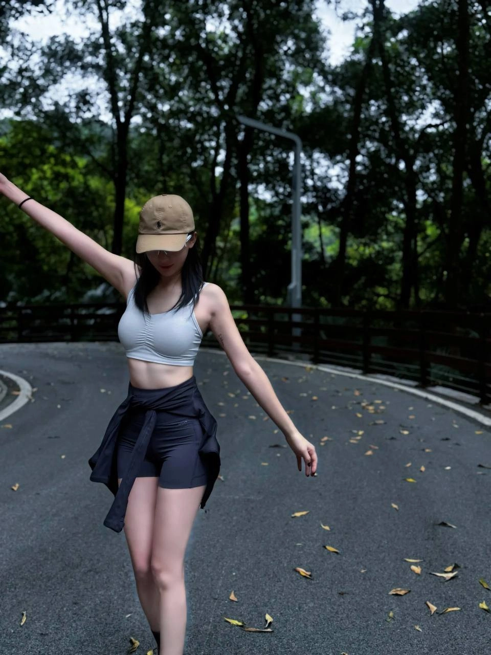 一位穿着棕色帽子和黑色短裤的女人在路上滑板。