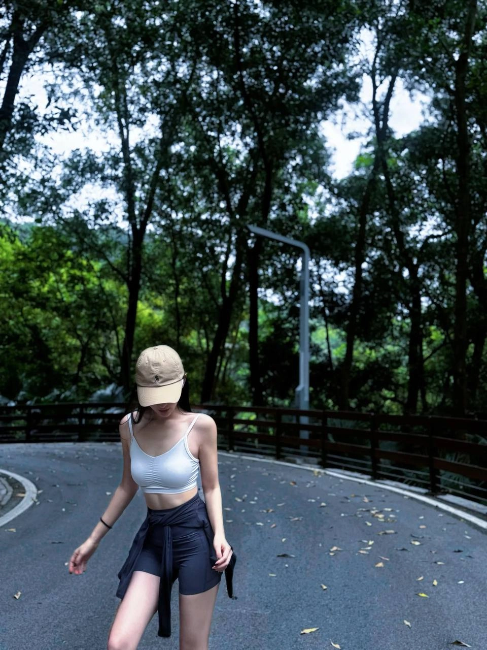 一位穿着棕色帽子和黑色短裤的女人在路上滑板。