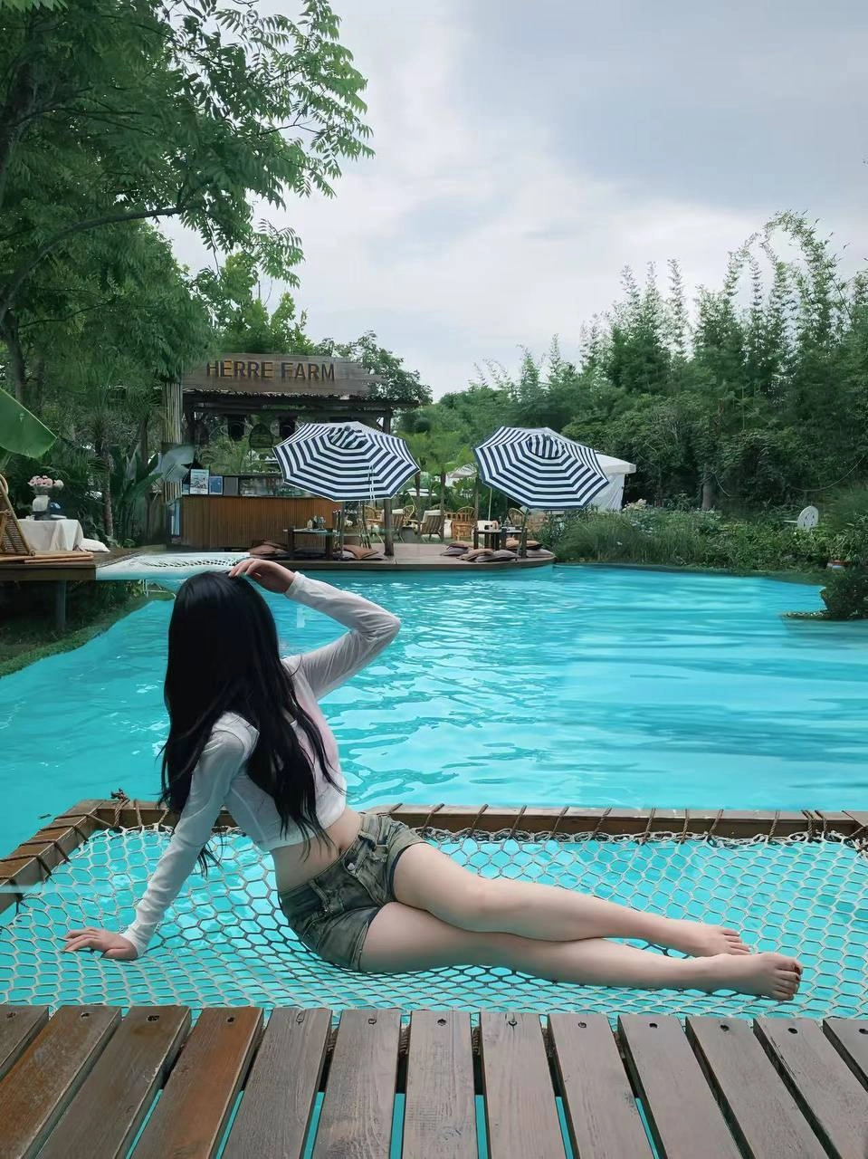 女人躺在一个锤子旁边的游泳池。