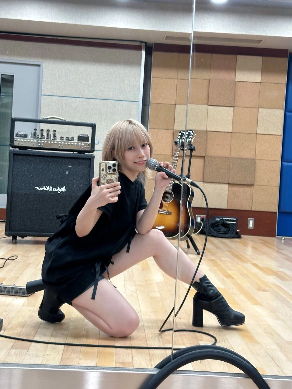 穿着黑色衣服的女人拿着手机和麦克风。