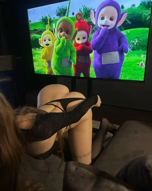 一位穿着黑色胸罩的女人坐在电视机前的沙发上。