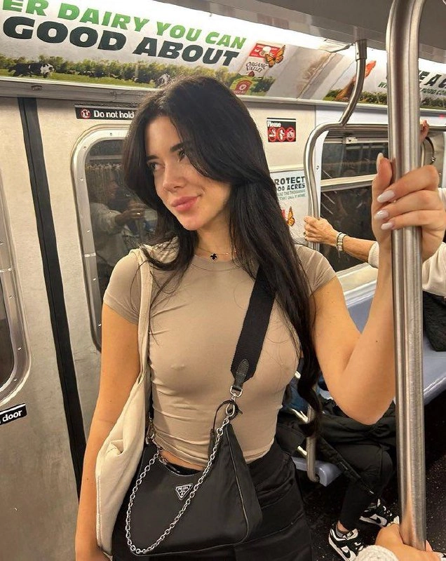 一位戴着黑色钱包和白色衬衫的妇女正在握着杆子。