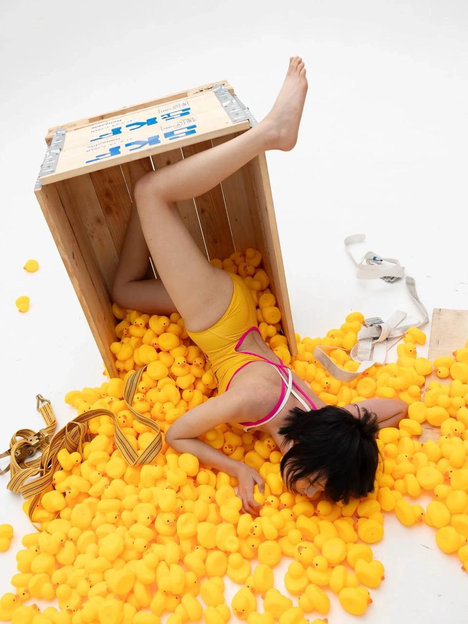 穿着黄色浴衣的女人被橡胶鸭子包围。