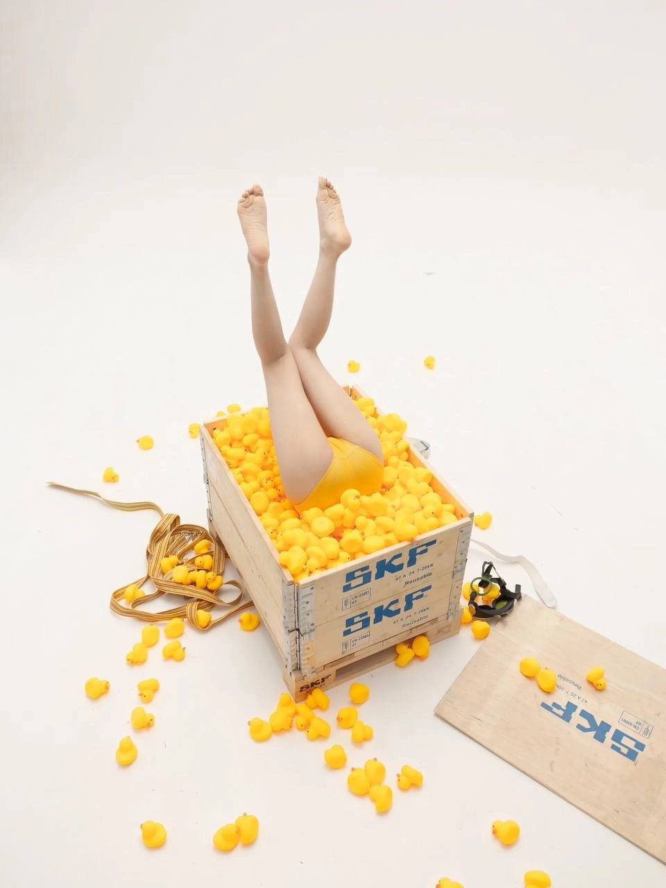 女人躺在一个装满黄色球的盒子上。