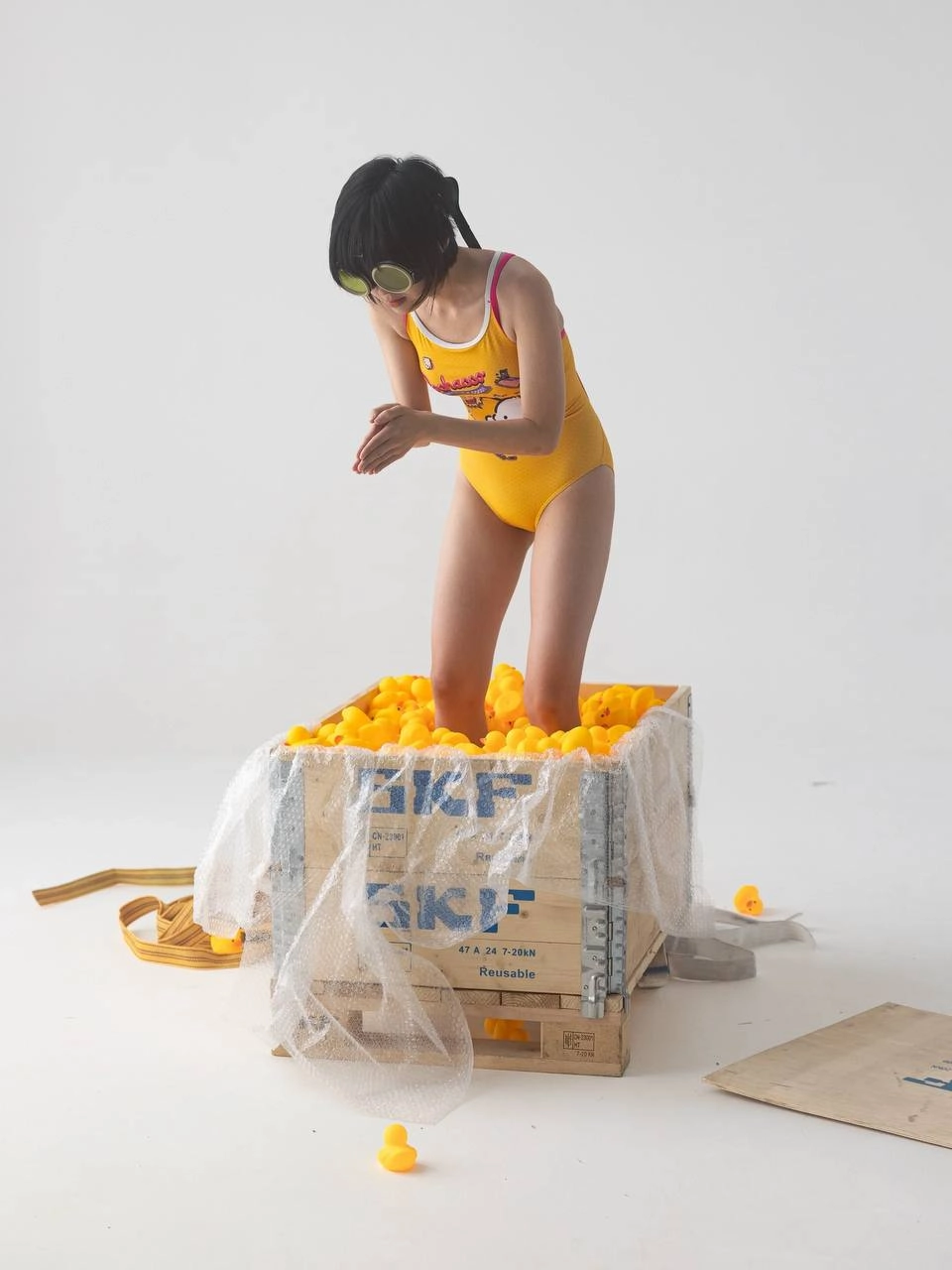 女孩在一个装满黄橡胶鸭子的盒子里。