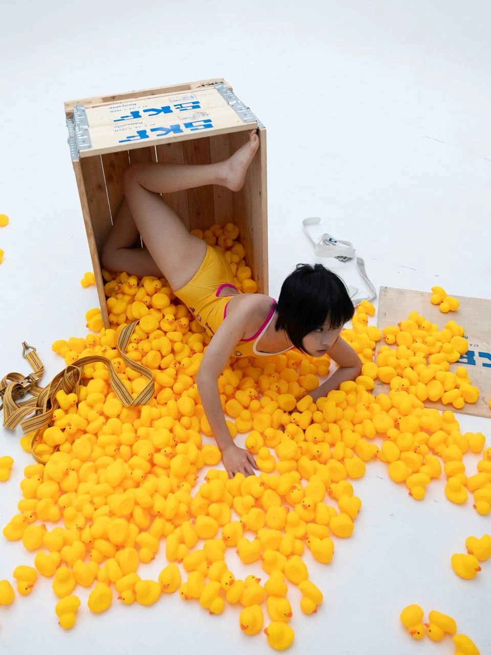 穿着黄色浴衣的女人被橡胶鸭子包围。