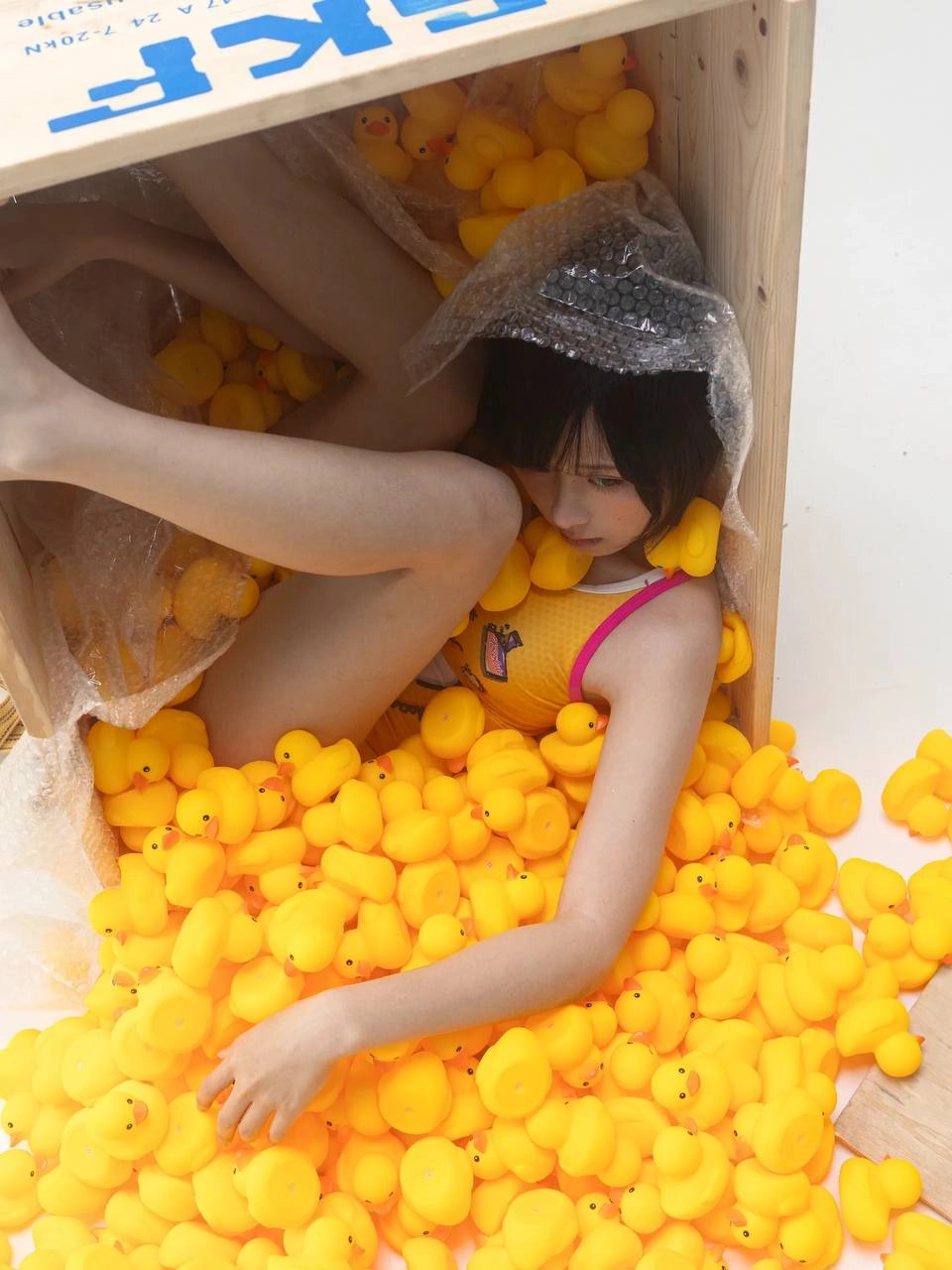 女人躺在一个装满黄色球的盒子上。