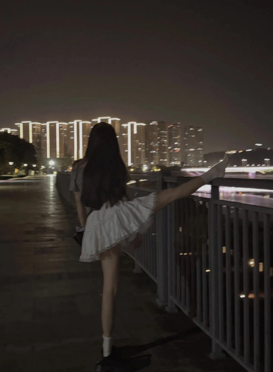 长头发和白色裙子的女人在夜间走在街道上。