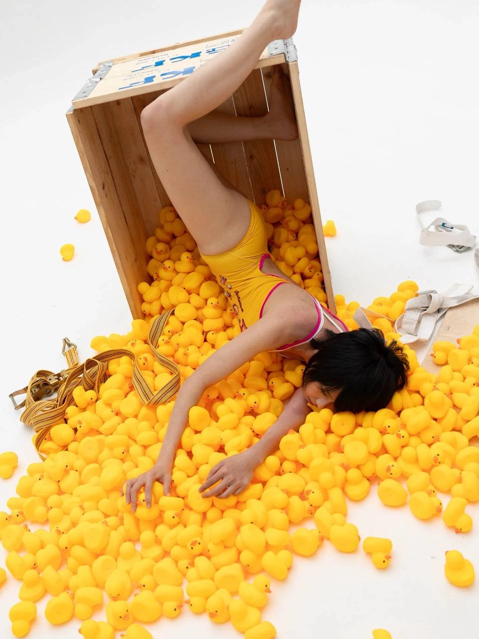 穿着黄色浴衣的女人被橡胶鸭子包围。