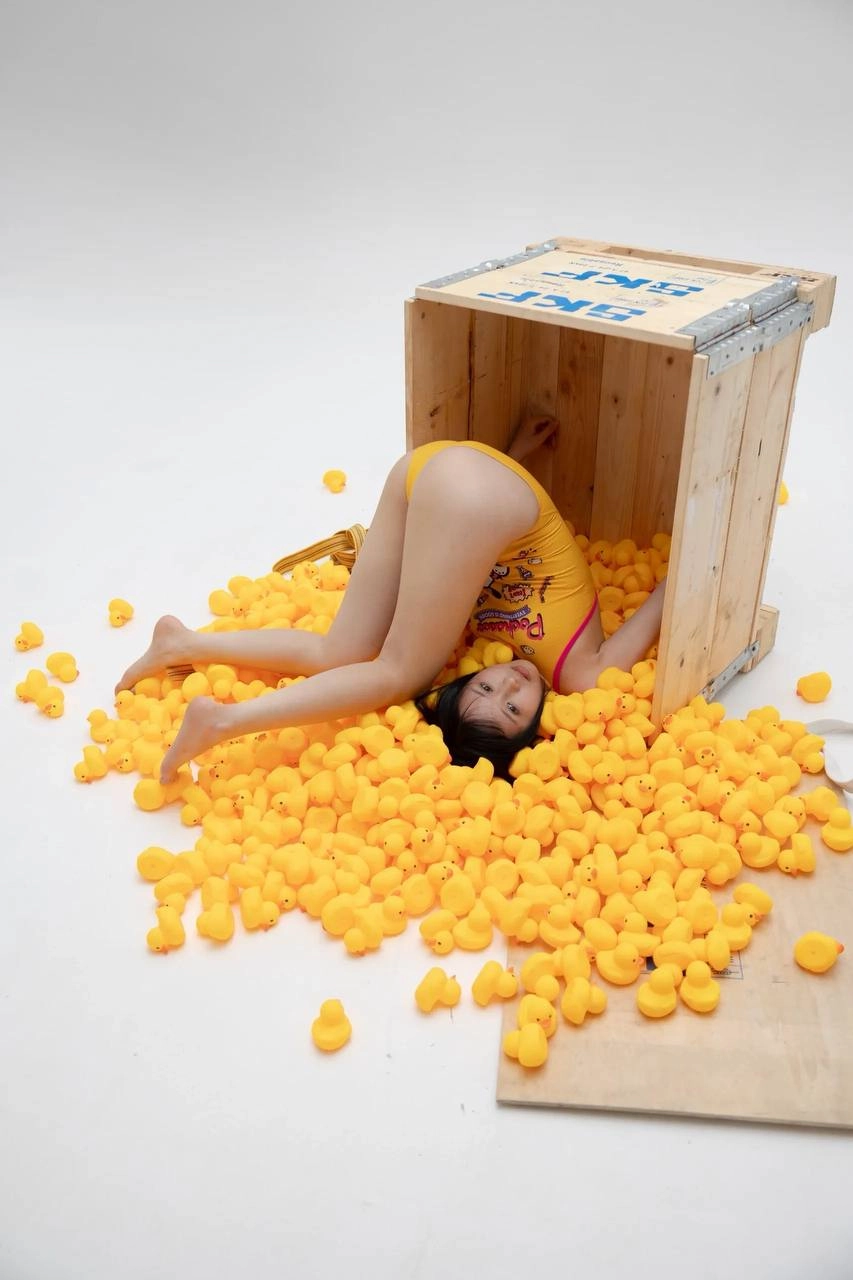 女人躺在一个装满黄色球的盒子上。