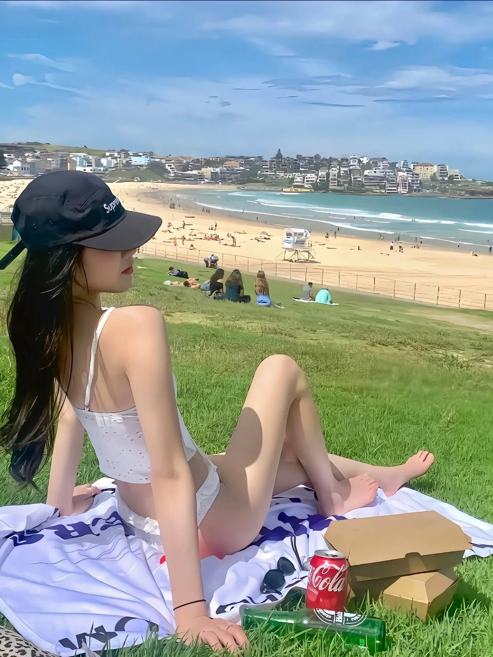 一位穿着白色比基尼的女人站在一座草地山上。