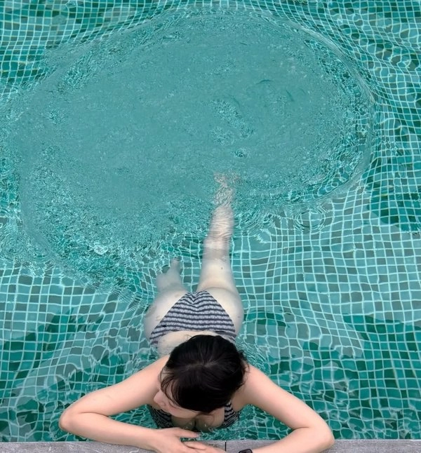 一位穿比基尼的女人躺在泳池的背上。