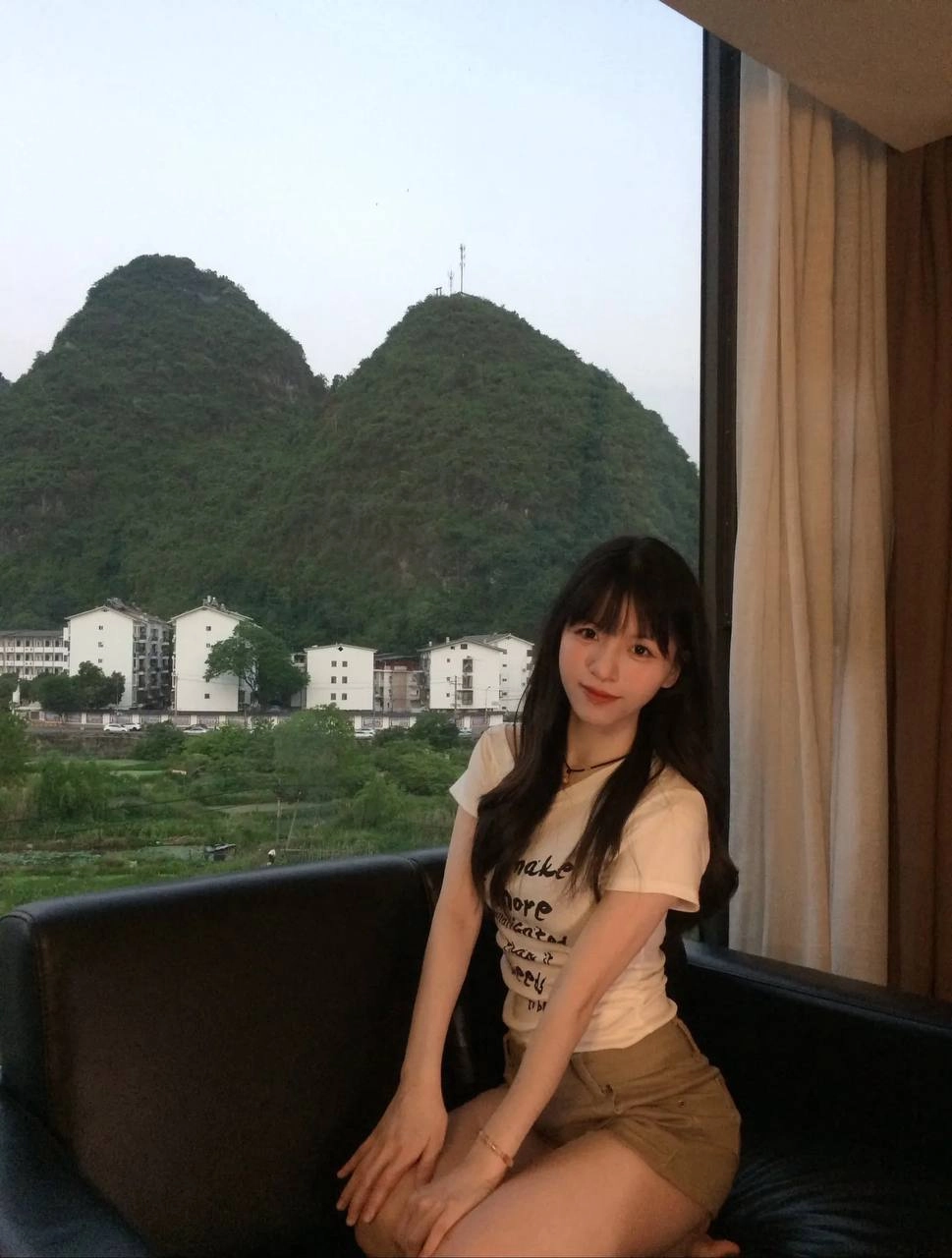 女人坐在沙发上,望着一座山。