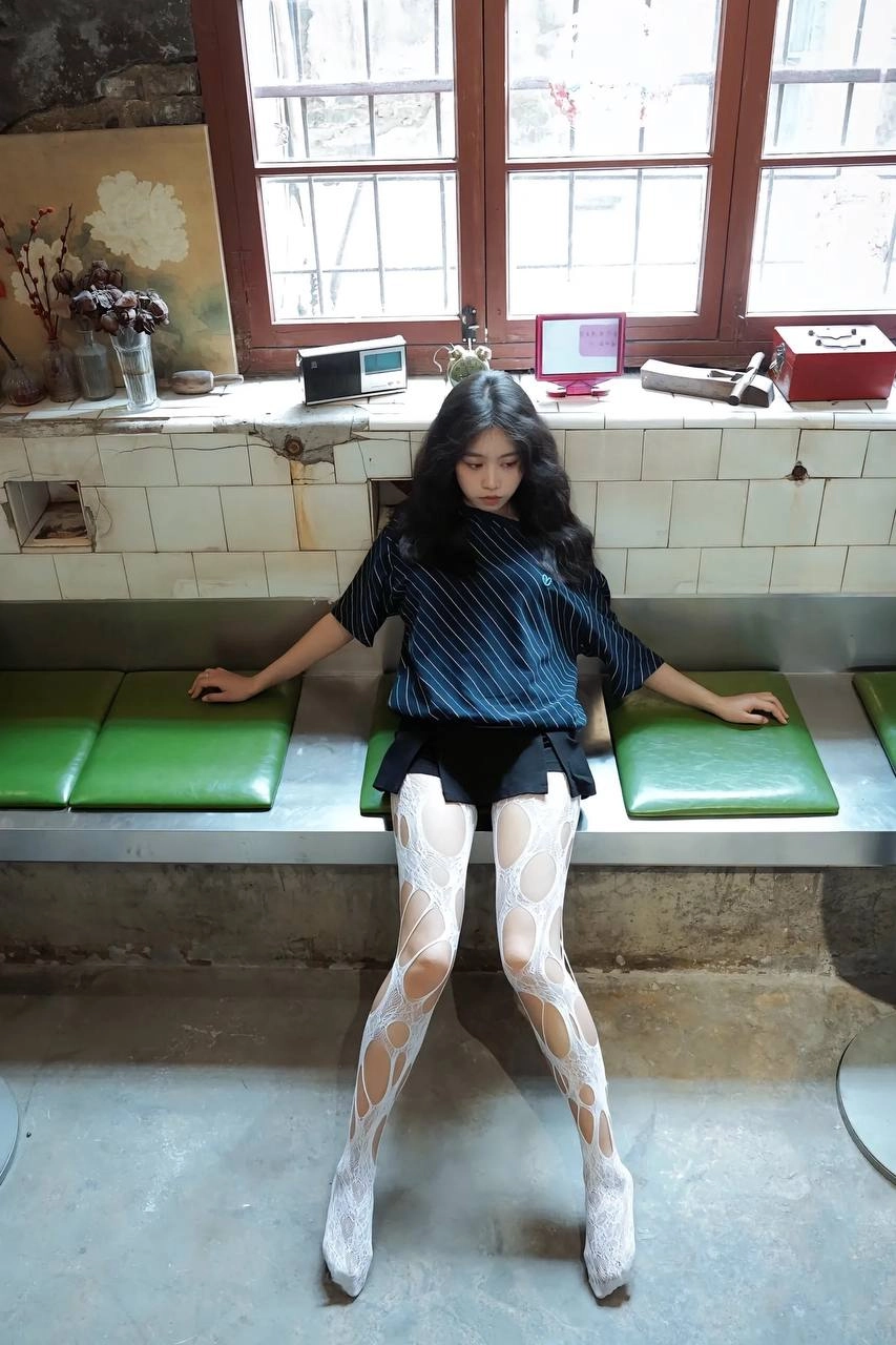 穿着白色裤子的女人坐在一个凳子上。