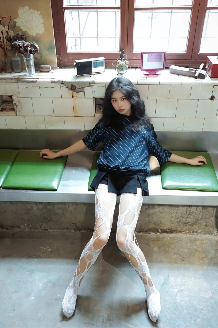 穿着白色裤子的女人坐在一个凳子上。