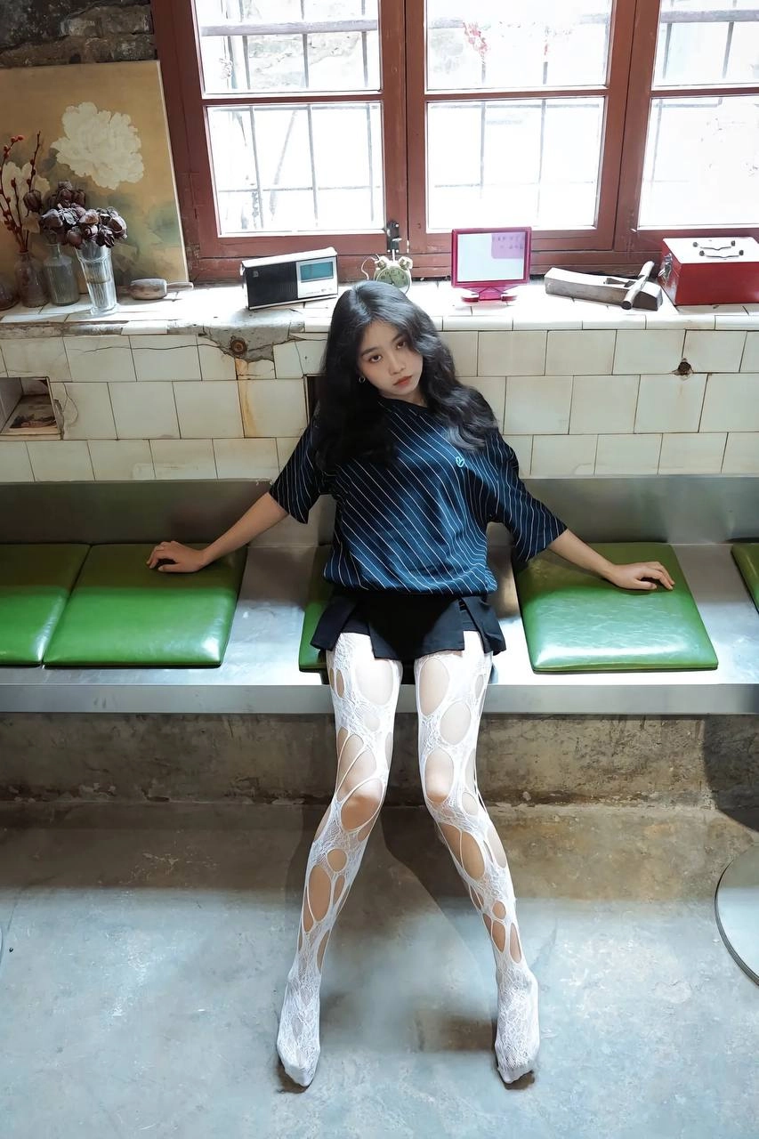 黑头发和白袜子的女人坐在一个凳子上。