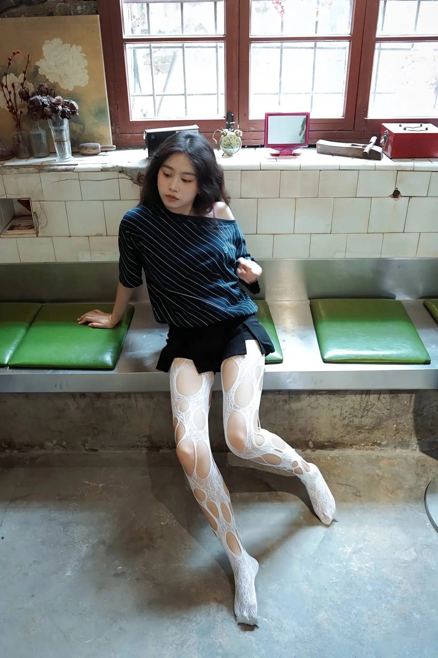 穿着白色裤子的女人坐在一个凳子上。