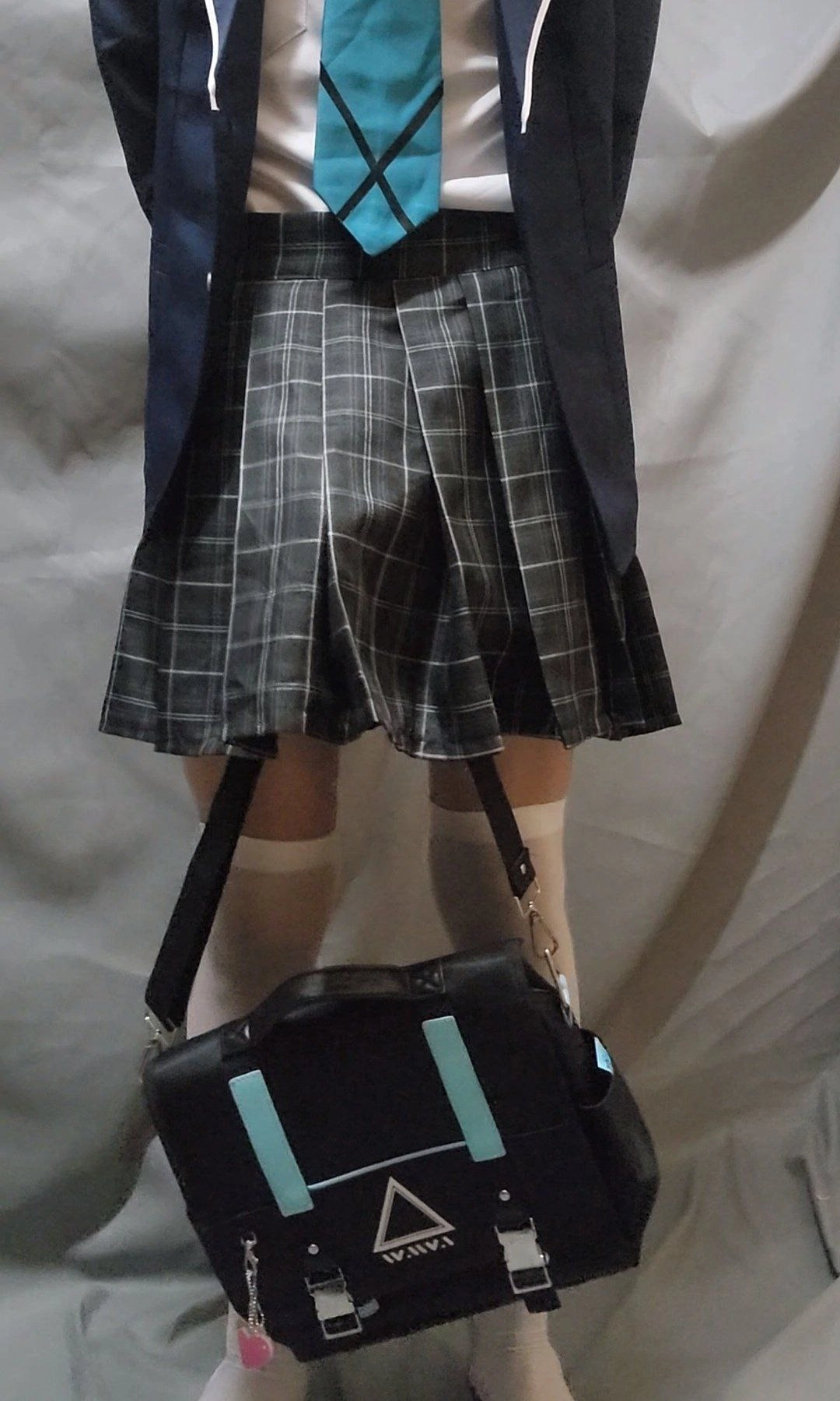 女人穿着一件白色裙子和一个蓝色和黑色袋子。